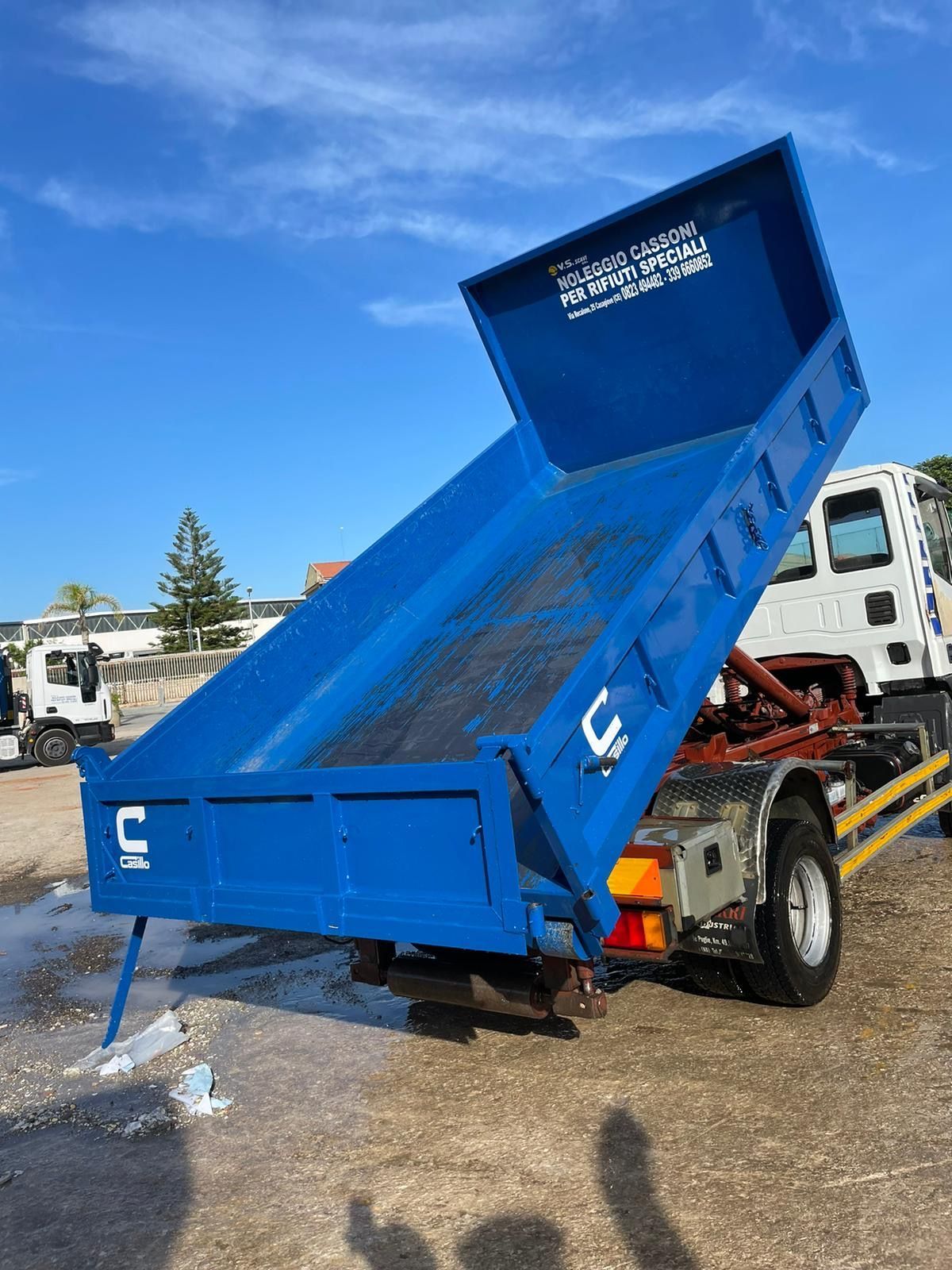 Un camion con cassone ribaltabile blu è parcheggiato in un parcheggio.