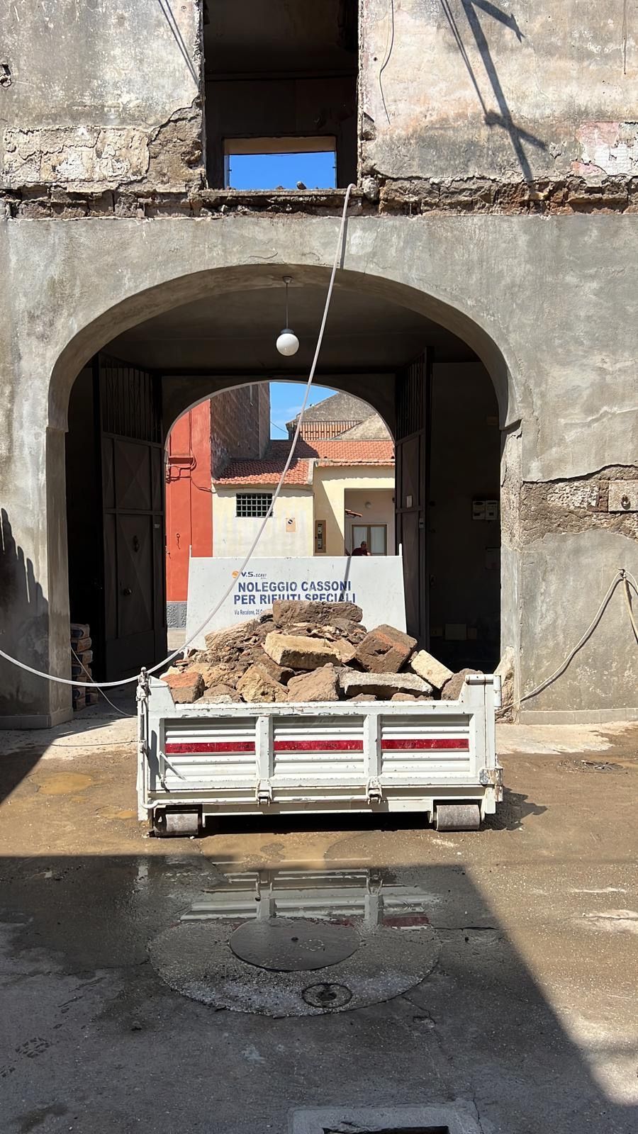 Un camion bianco trasporta una grande catasta di legna davanti a un edificio.