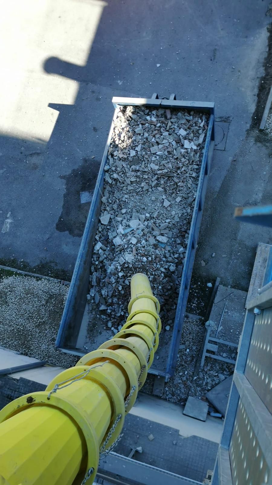 Un tubo giallo esce da un camion pieno di pietre.