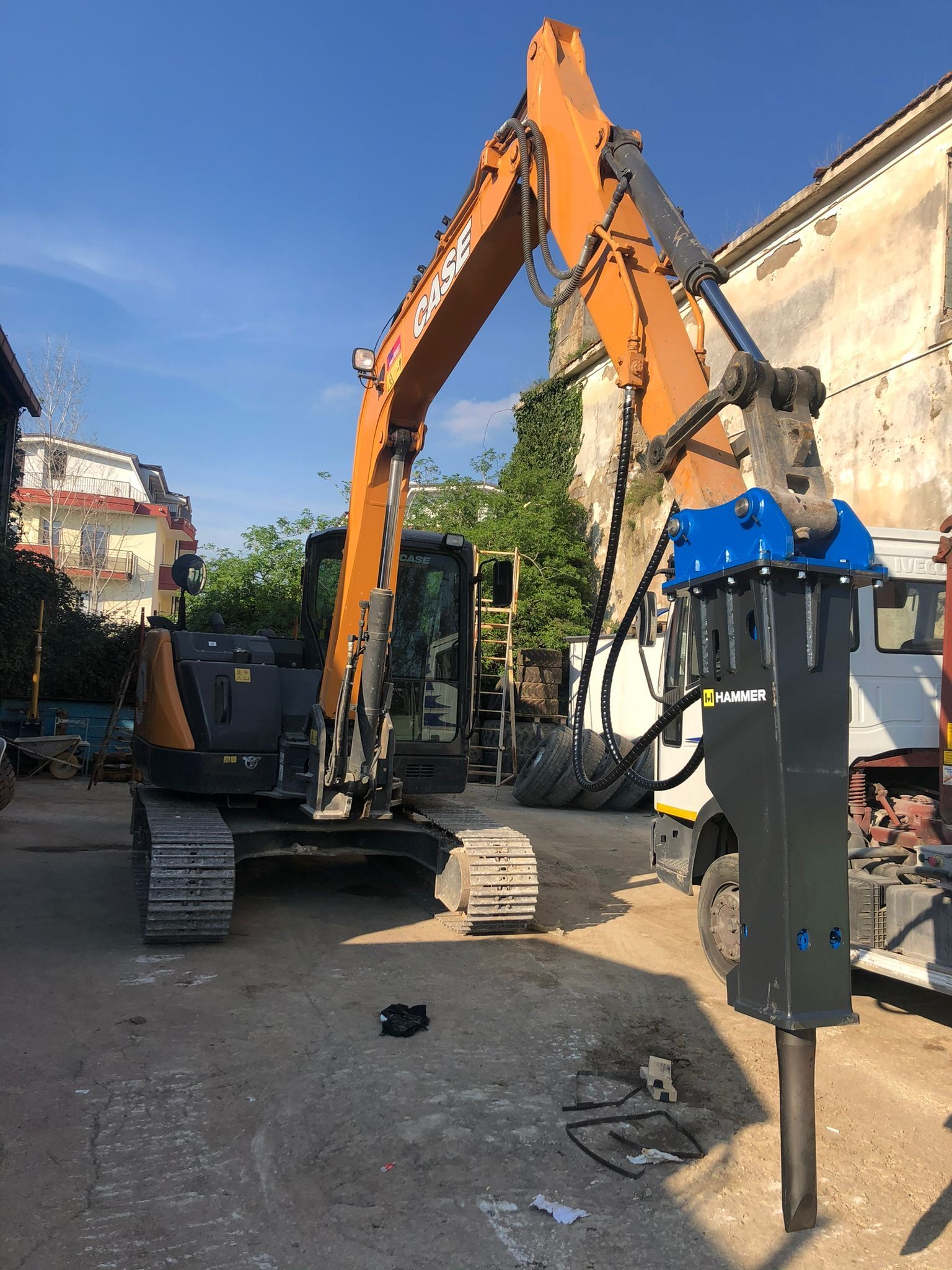 Un grande escavatore è parcheggiato in un parcheggio accanto a un camion.