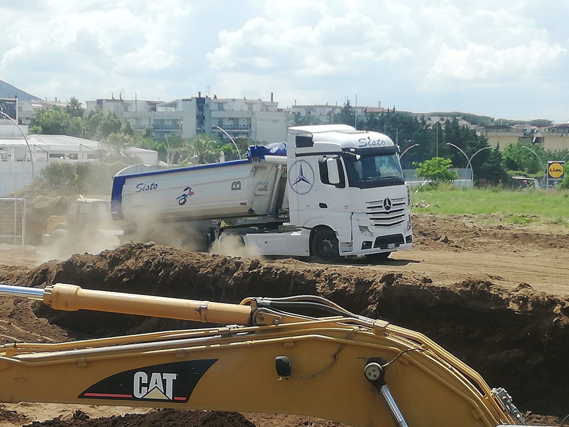 Un camion con cassone ribaltabile sta guidando attraverso un campo sterrato
