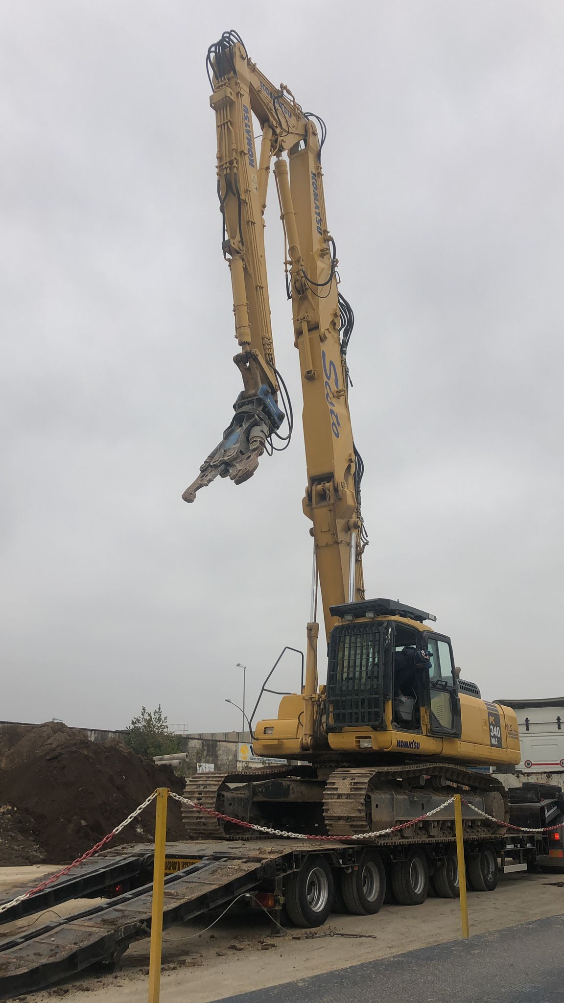 Un grande escavatore giallo è posizionato sopra un rimorchio.