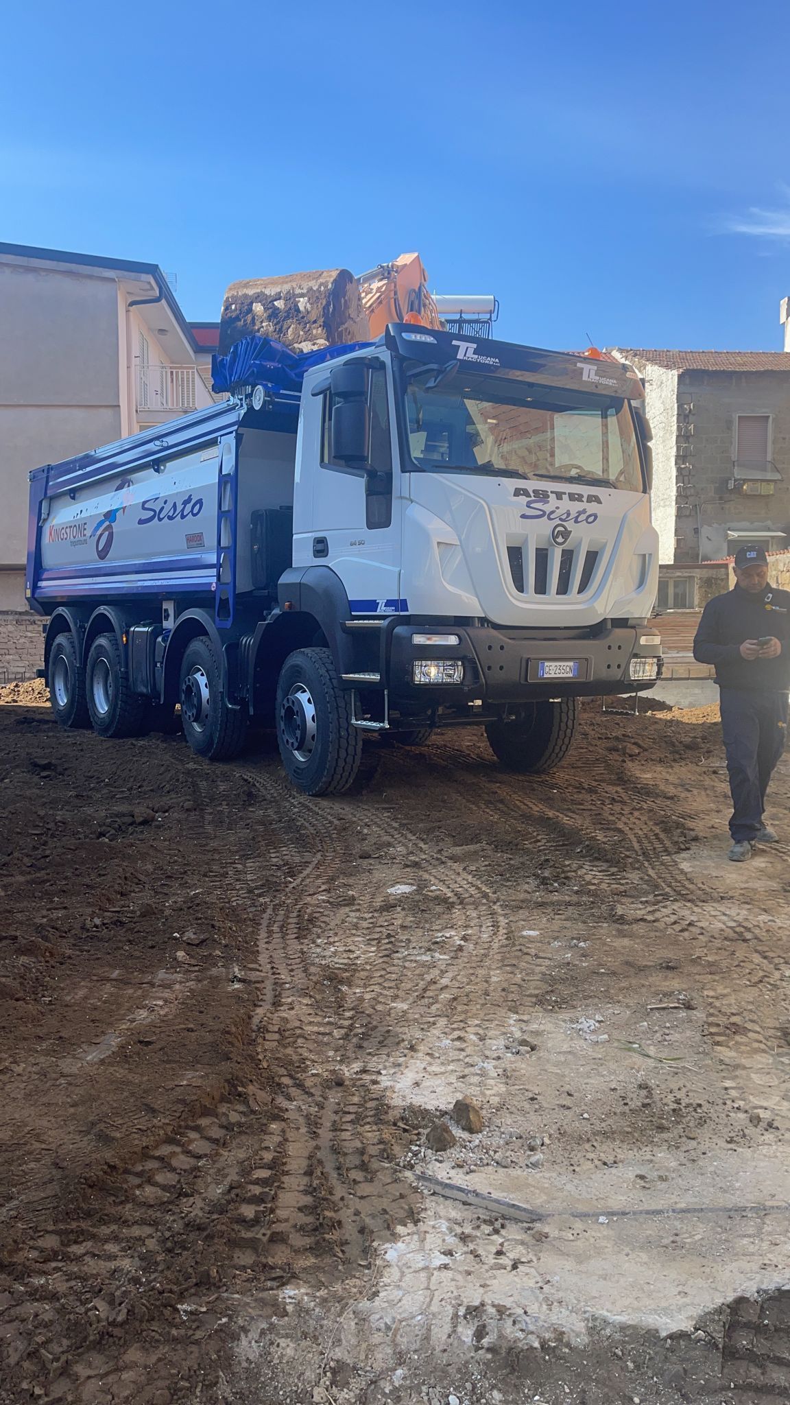 Un autocarro con cassone ribaltabile è parcheggiato in un campo sterrato.