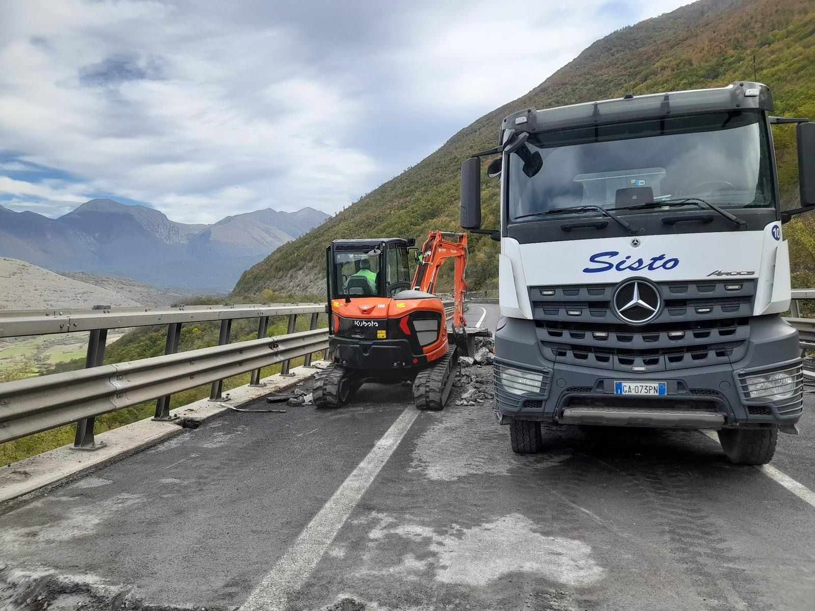 Un camion e un escavatore sono parcheggiati sul ciglio della strada.