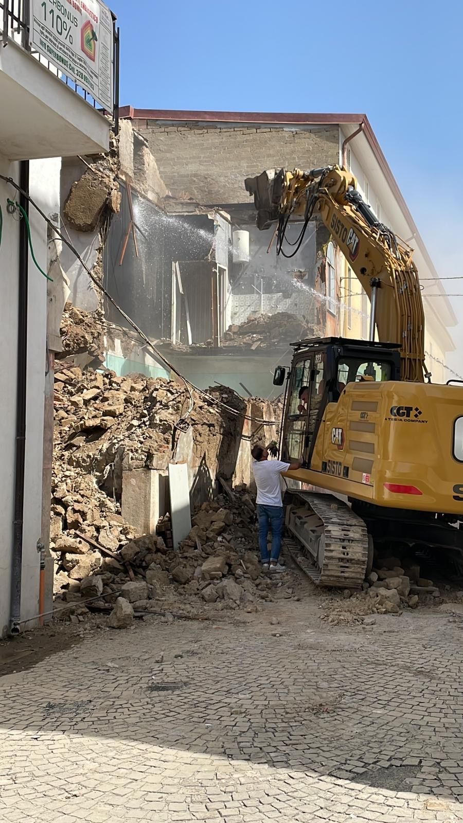 Una ruspa sta demolendo un edificio in una città.