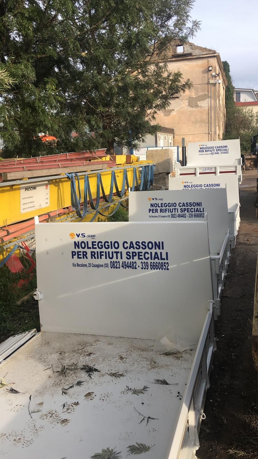 Una fila di cassoni bianchi con un cartello che dice noleggio cassoni per rifiuti speciali.