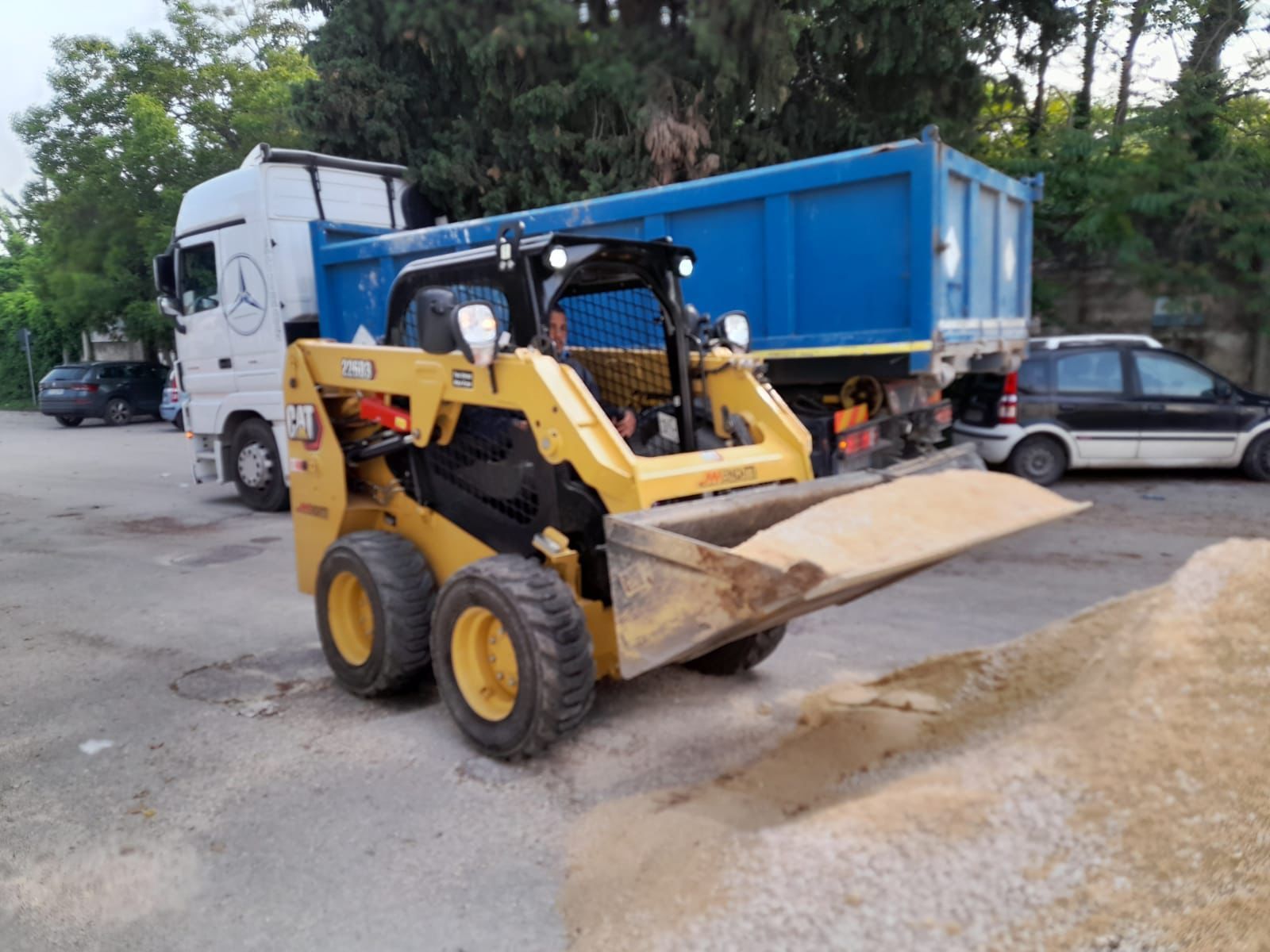 Una ruspa è parcheggiata accanto a un autocarro con cassone ribaltabile in un parcheggio.