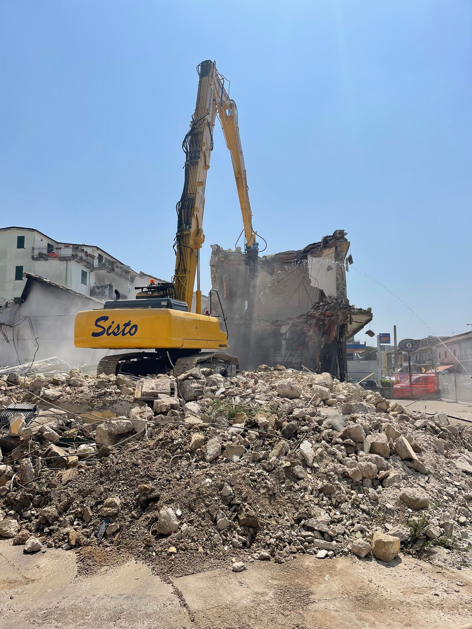 Un grande escavatore giallo sta demolendo un edificio