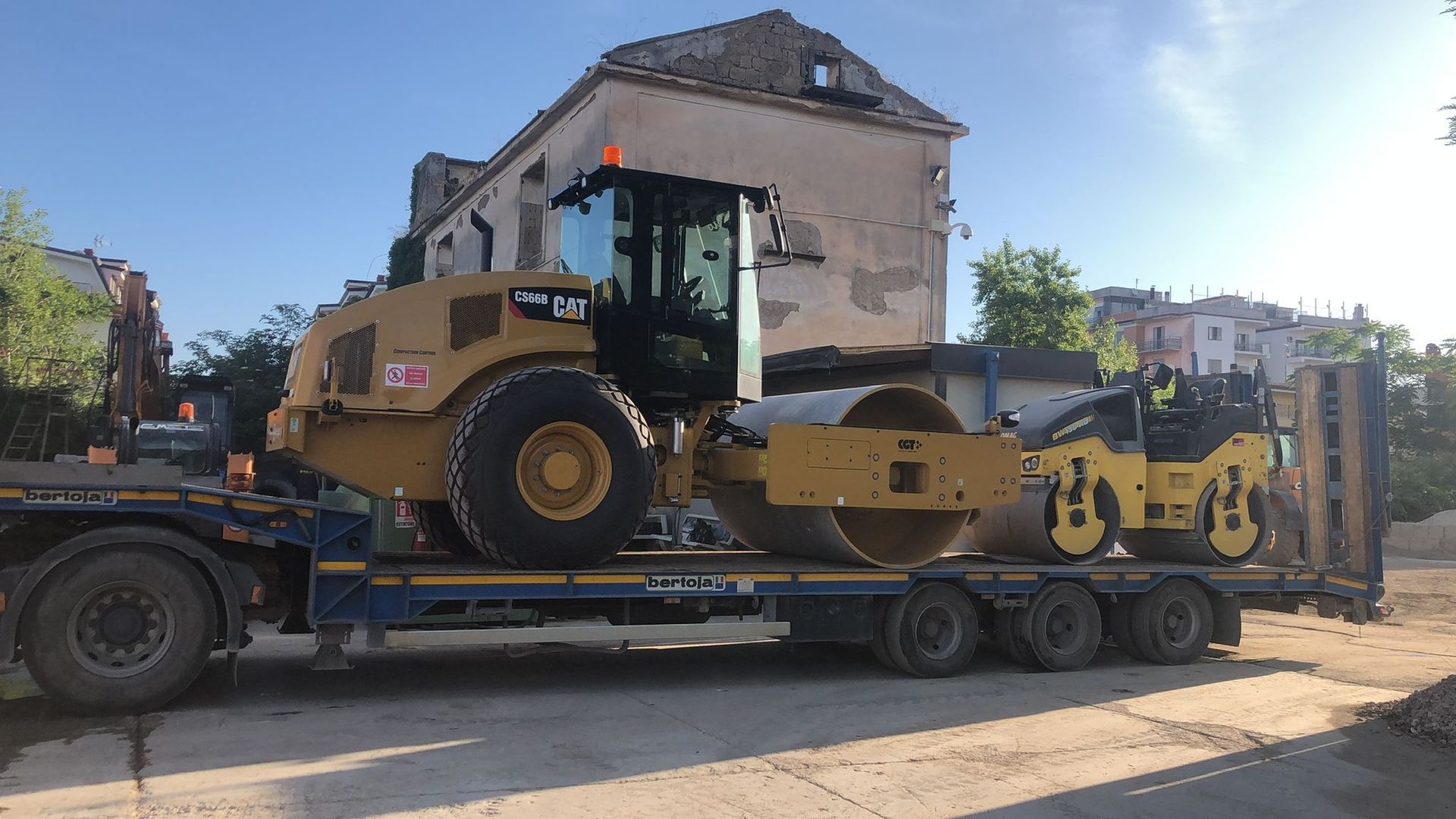 Un grande trattore giallo è parcheggiato sopra un rimorchio.