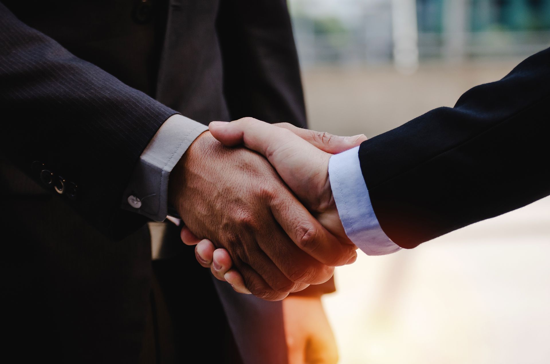 Two businessmen are shaking hands in a close up of their hands.