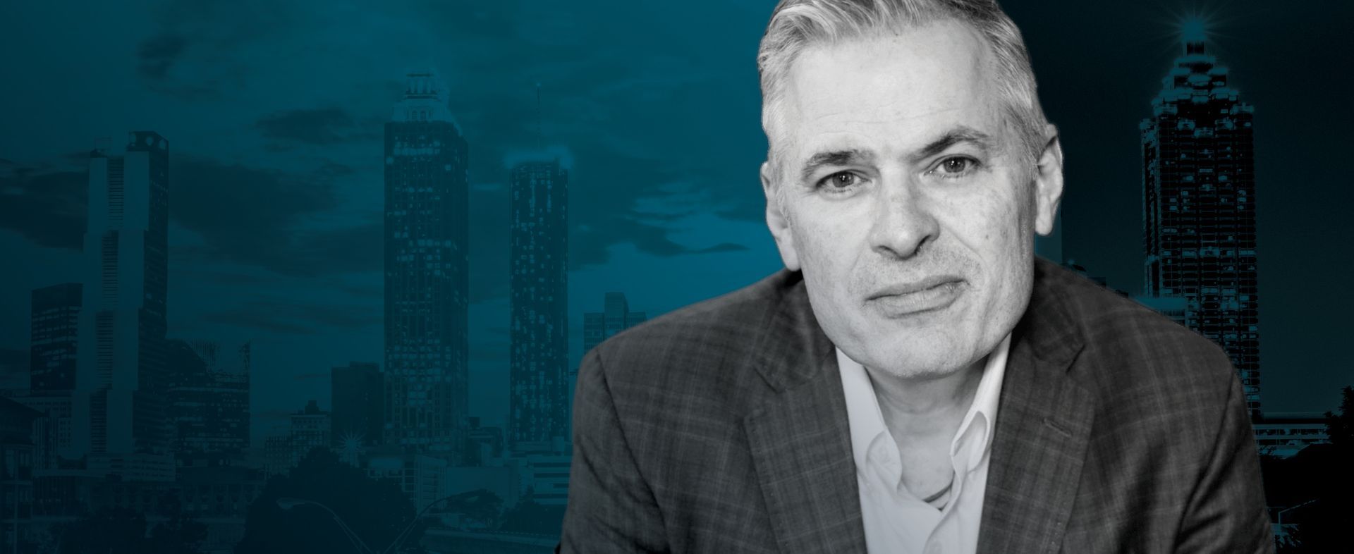 Man in suit jacket, with city backdrop.