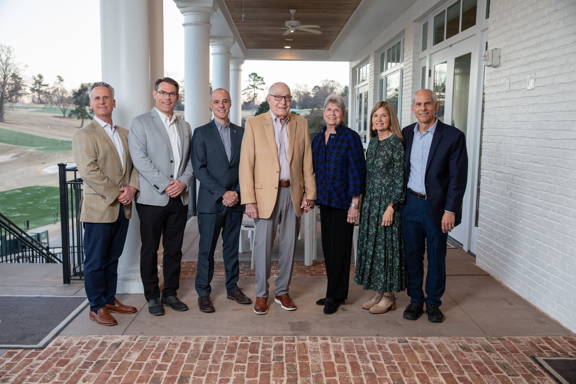 A group of people are standing next to each other on a porch.