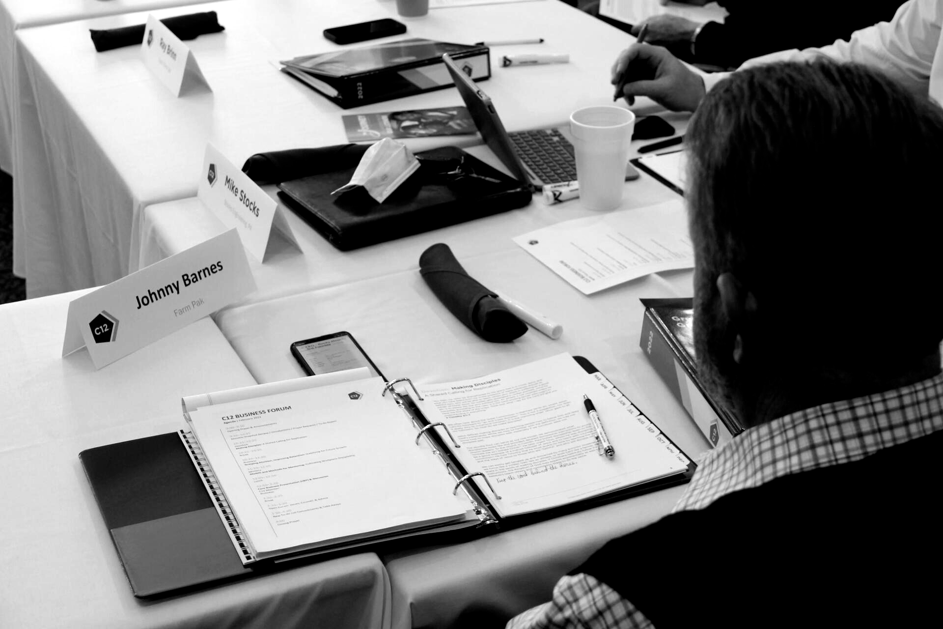 A black and white photo of a group of people sitting at a table.