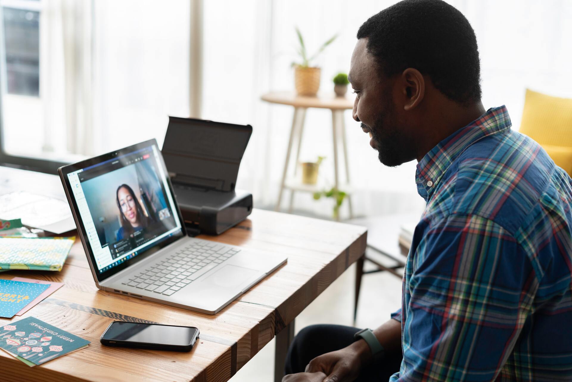 a man is sitting at a table using a laptop computer to have a video call with a woman .