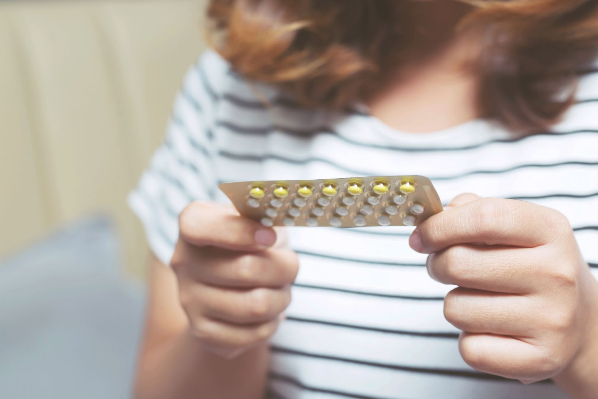 A woman is holding a pack of contraceptive pills in her hands.