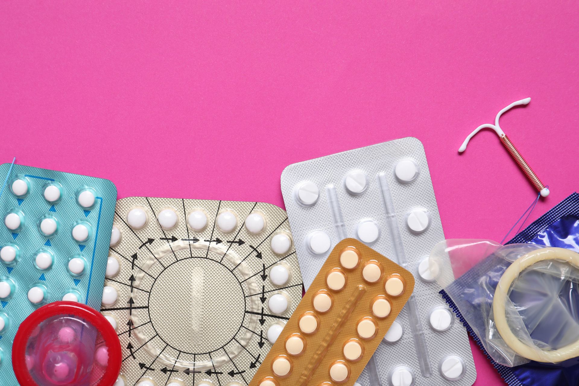 There are many different types of contraceptives on a pink background.