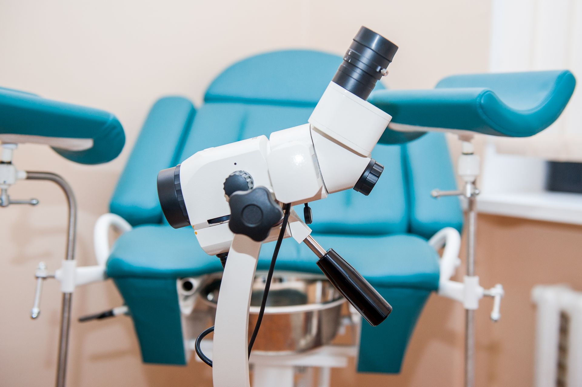 A gynecologist is taking a sample from a patient in a gynecological chair.