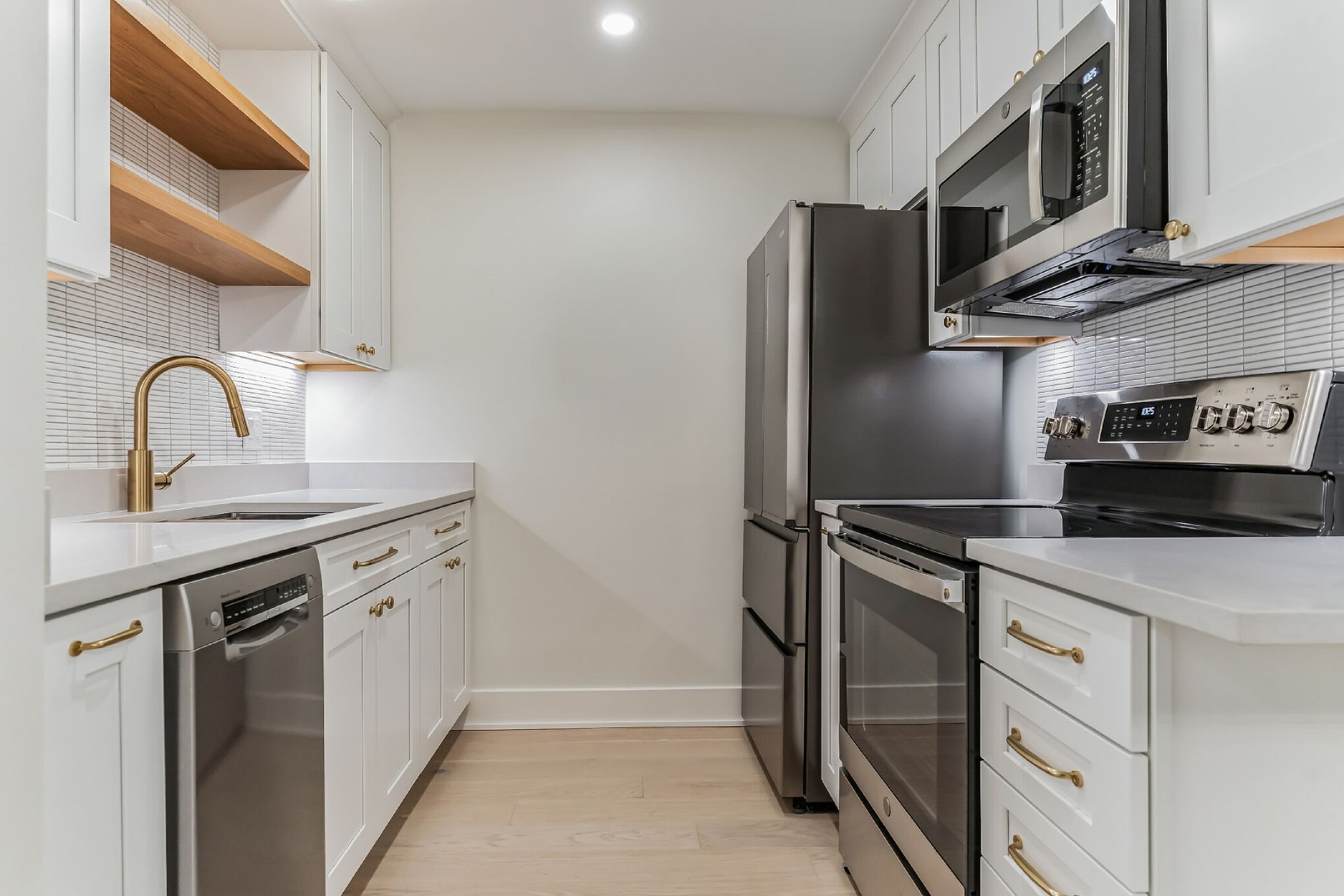 modern galley kitchen with white cabinets brass hardware stainless steel appliances tile backsplash small space remodel ideas