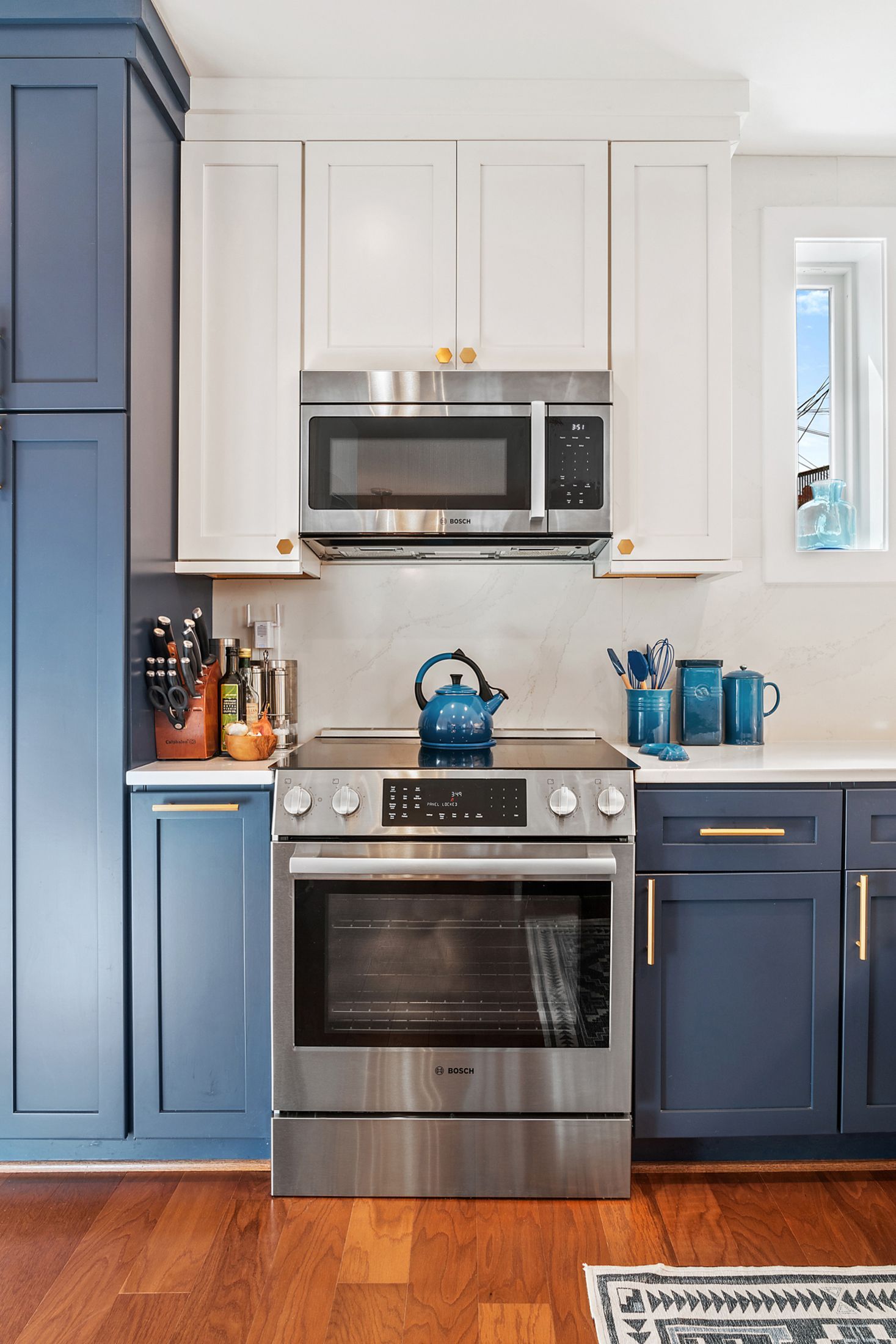 Blue and white kitchen with Bosch range, shaker cabinets, gold hardware, and quartz backsplash in historic DC remodel