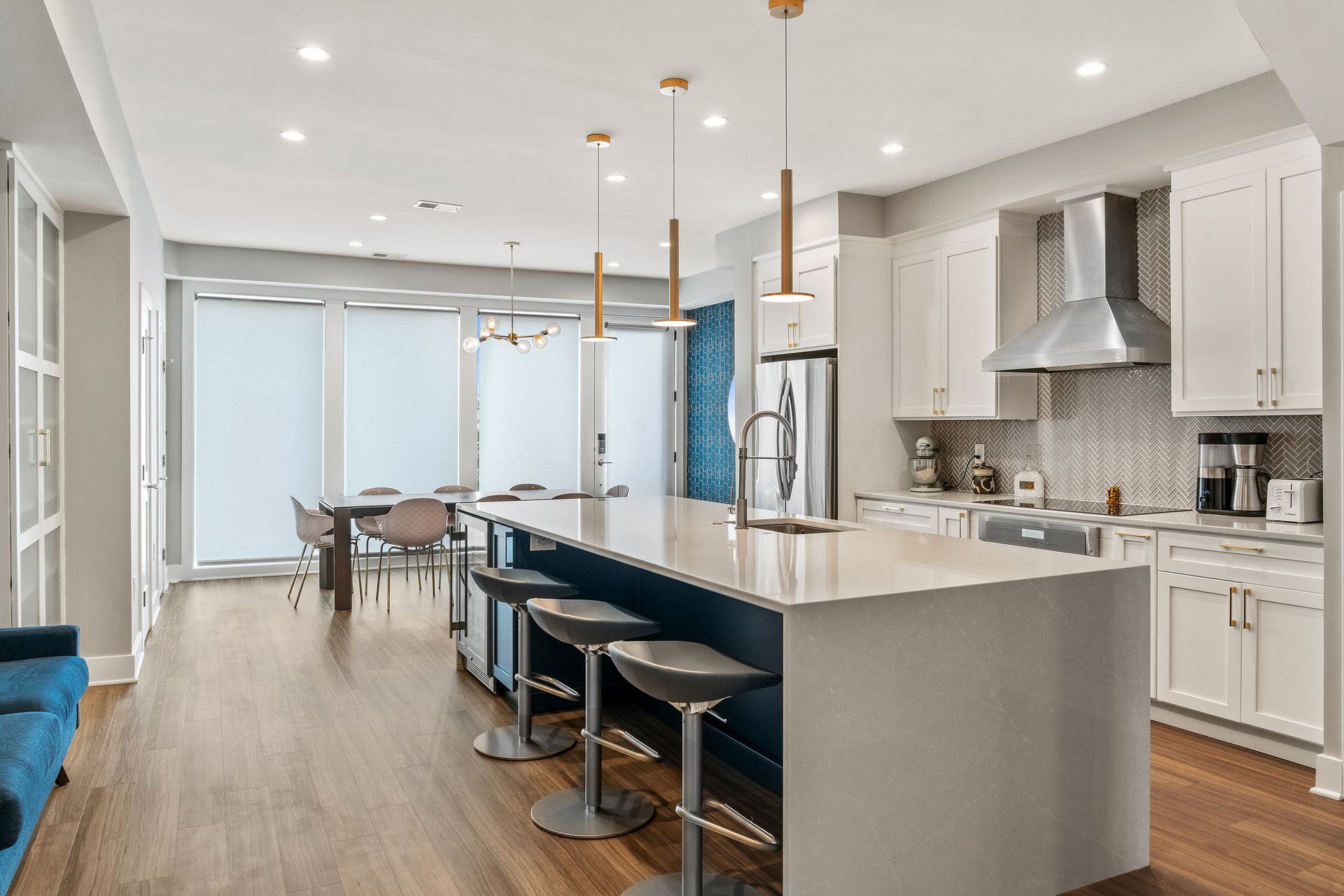Kitchen with island bar seating, modern light fixtures, and large dining windows with shades