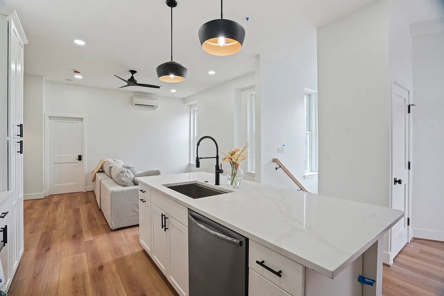 white kitchen island with quartz countertops, black faucet, black pendant lights, open concept living remodel