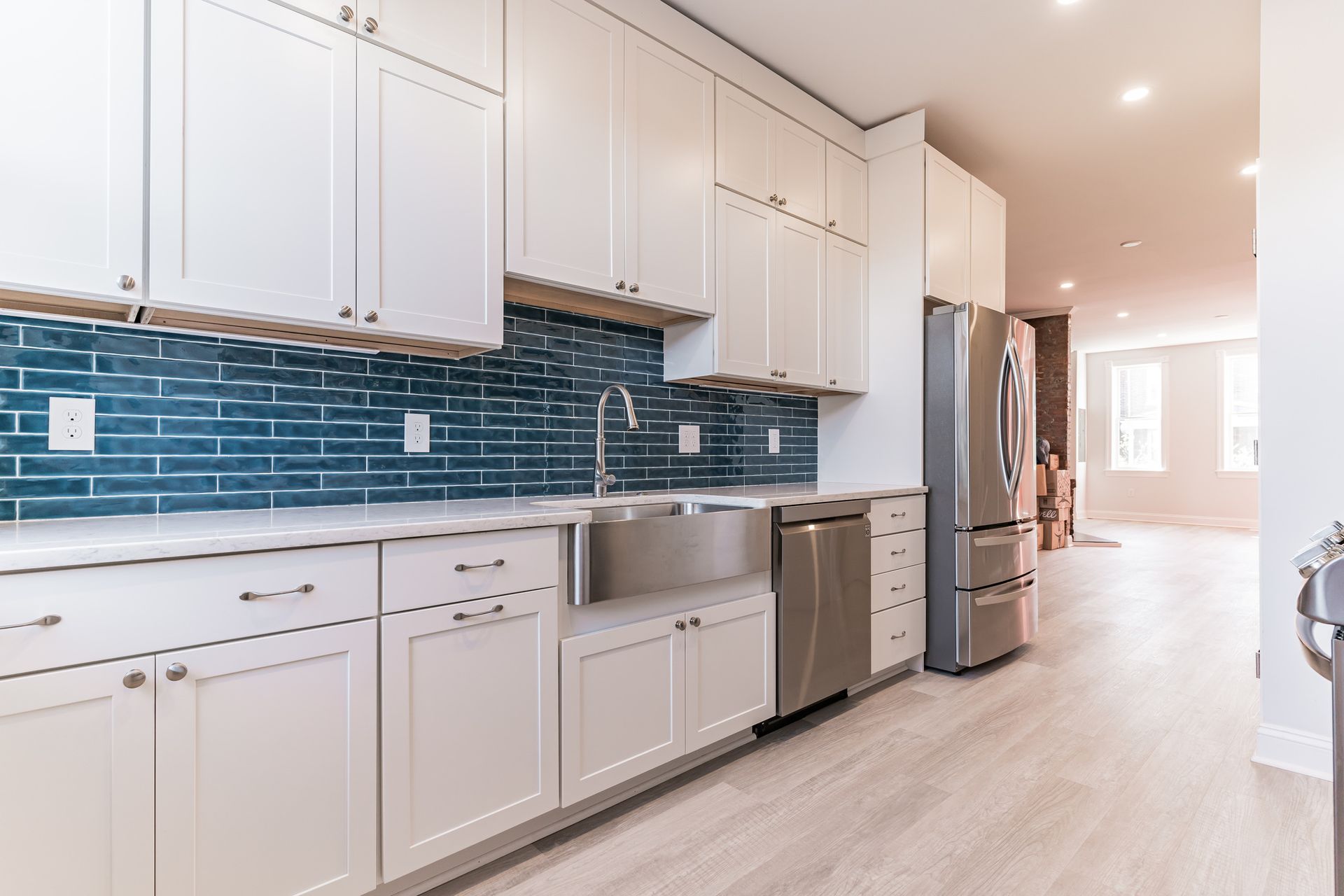 Kitchen with white shaker cabinets, blue subway tile backsplash, stainless steel farmhouse sink, and appliances