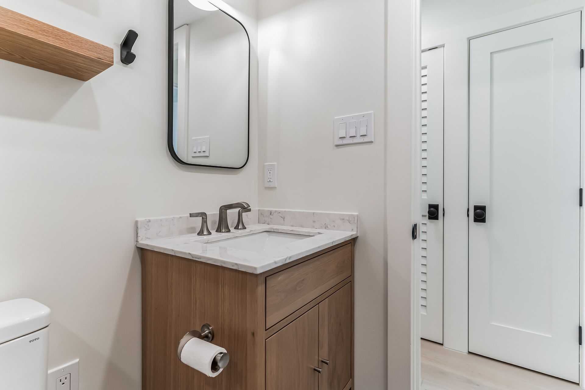modern bathroom remodel with light wood vanity, marble countertop, and black-framed mirror in washington dc historic home
