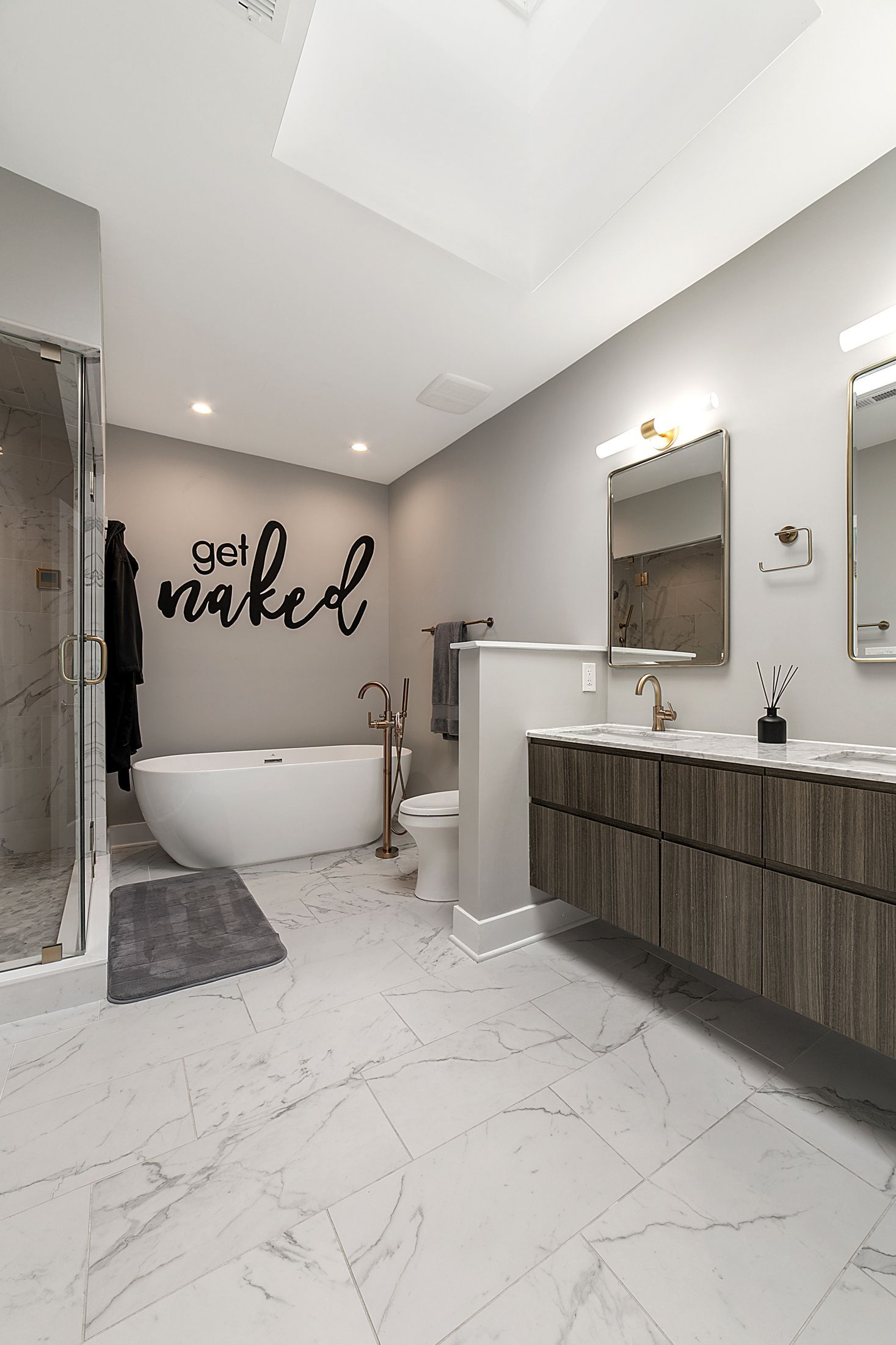 Modern bathroom with freestanding tub, floating double vanity, marble tile floor, and brass fixtures