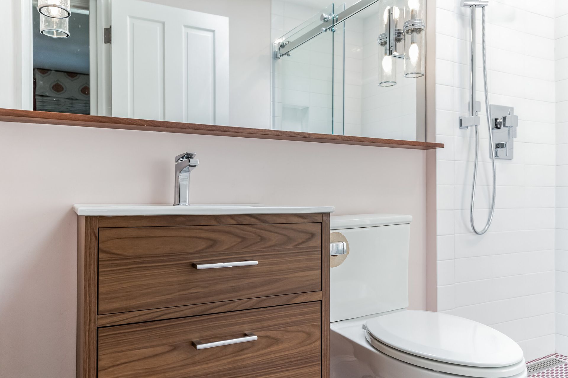 modern bathroom vanity with wood drawers, white countertop, toilet, and glass shower with chrome fixtures and tile walls