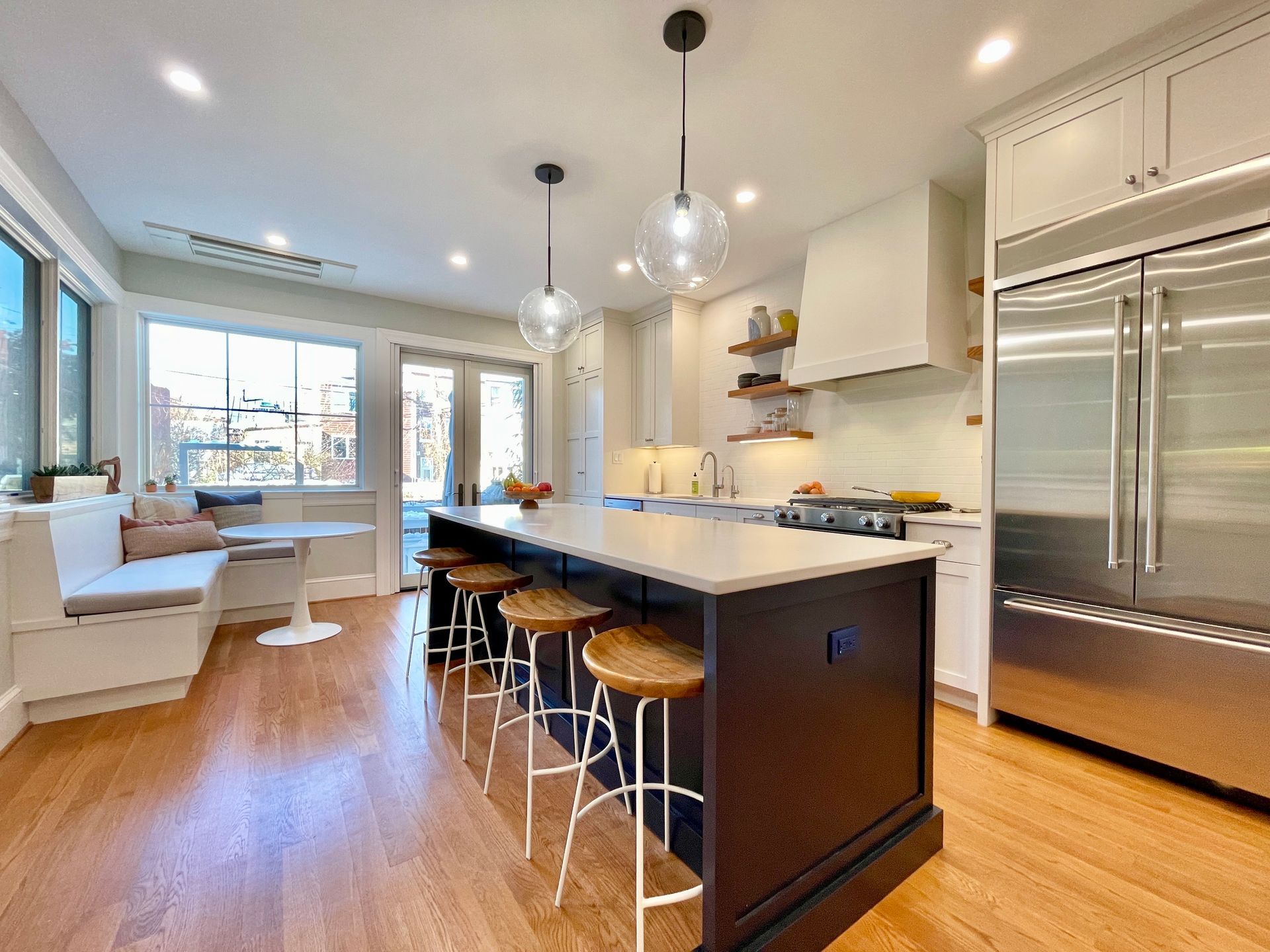modern kitchen island built-in banquette globe pendant lights white cabinets open shelving
