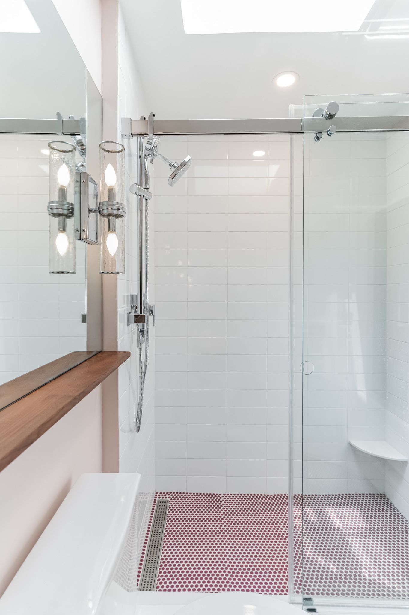 modern bathroom shower with glass door, white tile walls, chrome fixtures, red penny tile floor, and built-in bench
