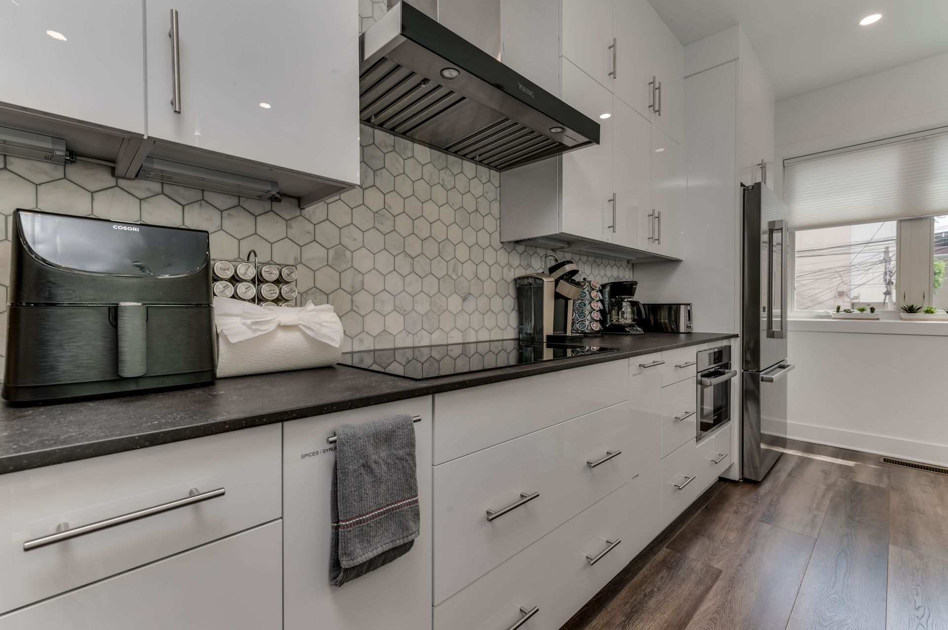 Modern kitchen with hex tile backsplash, black countertops, and stainless steel appliances