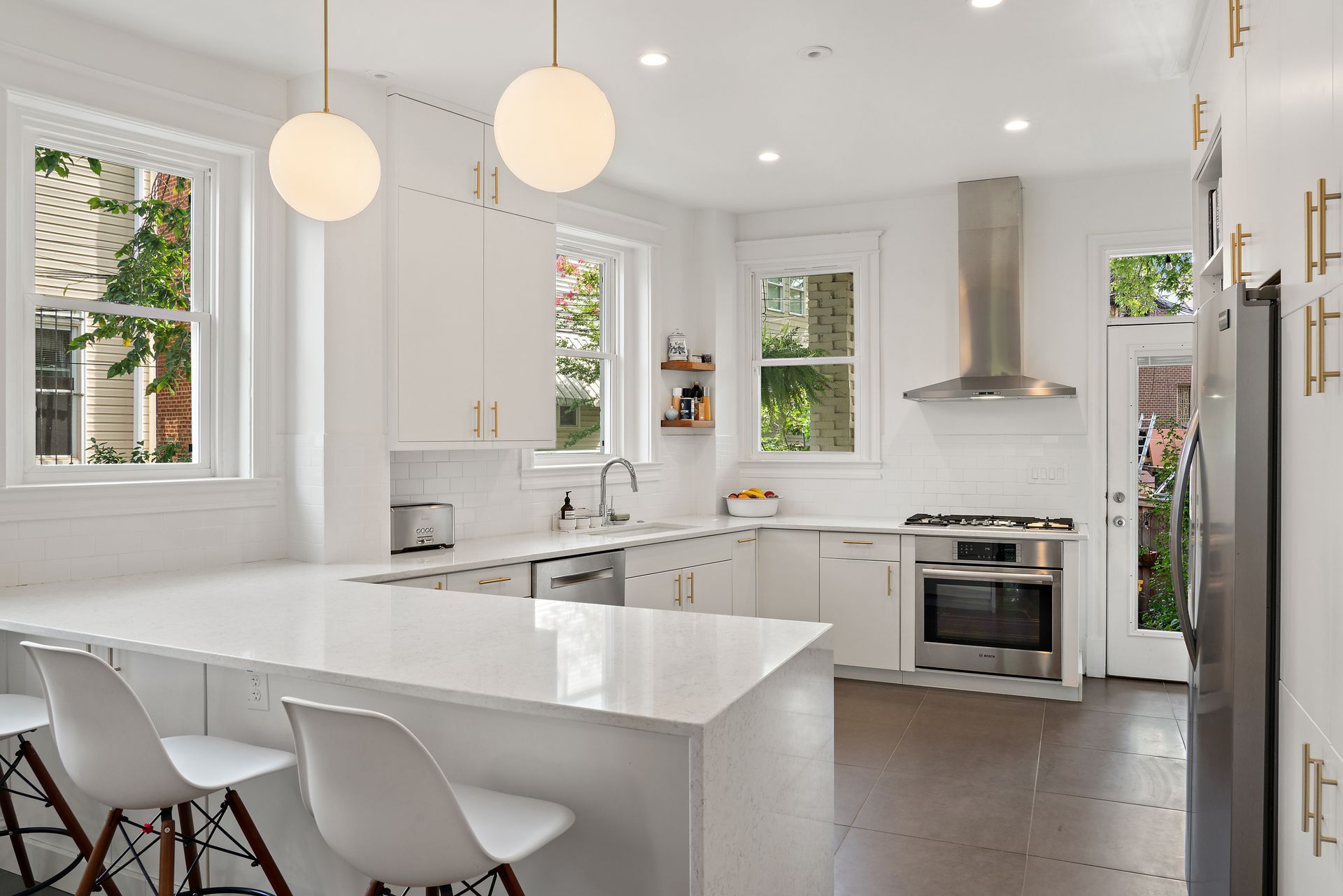 white modern kitchen remodel with breakfast bar seating, brass hardware, quartz countertops, and stainless appliances