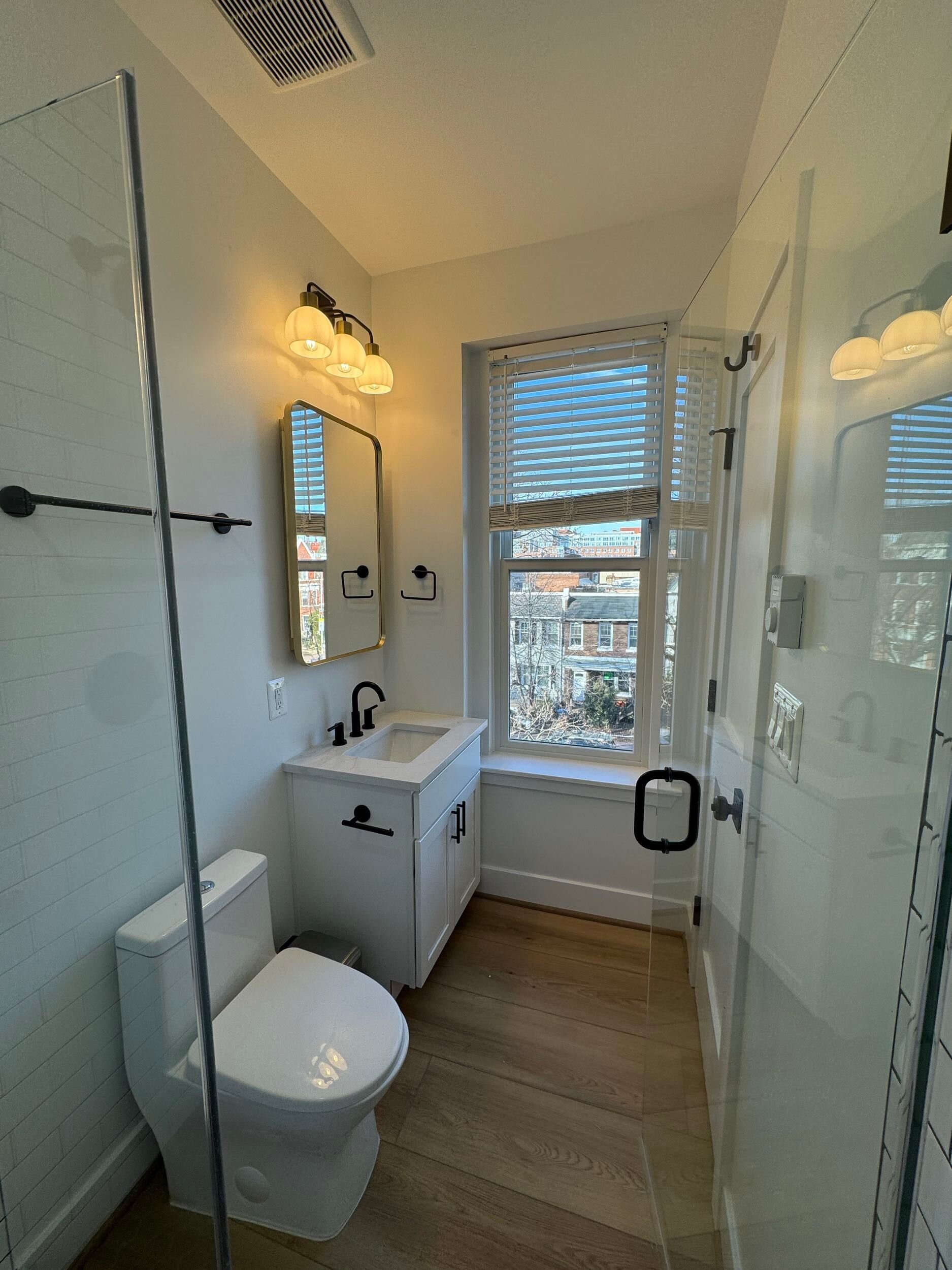 narrow bathroom remodel white vanity glass shower black fixtures window natural light