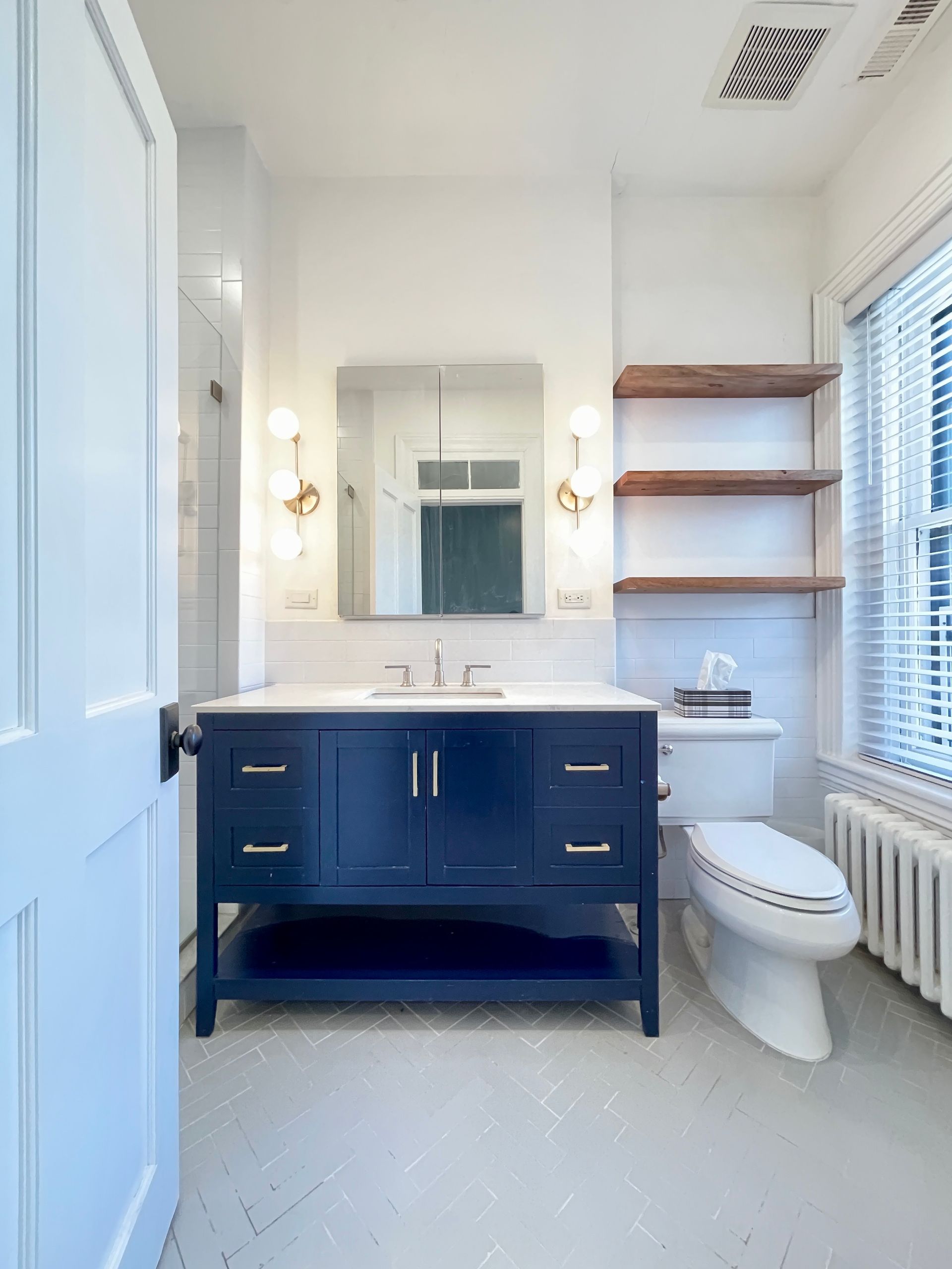 blue bathroom vanity with white tile, open wood shelves, and natural light in renovated historic Washington DC home