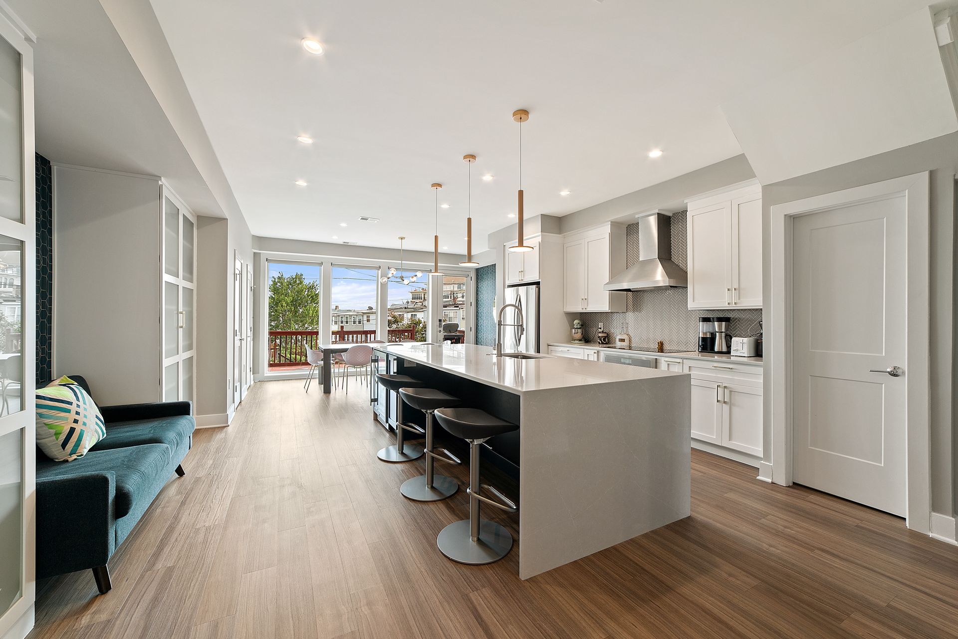 open concept kitchen remodel with large island, white cabinets, modern pendant lights, and stainless steel appliances
