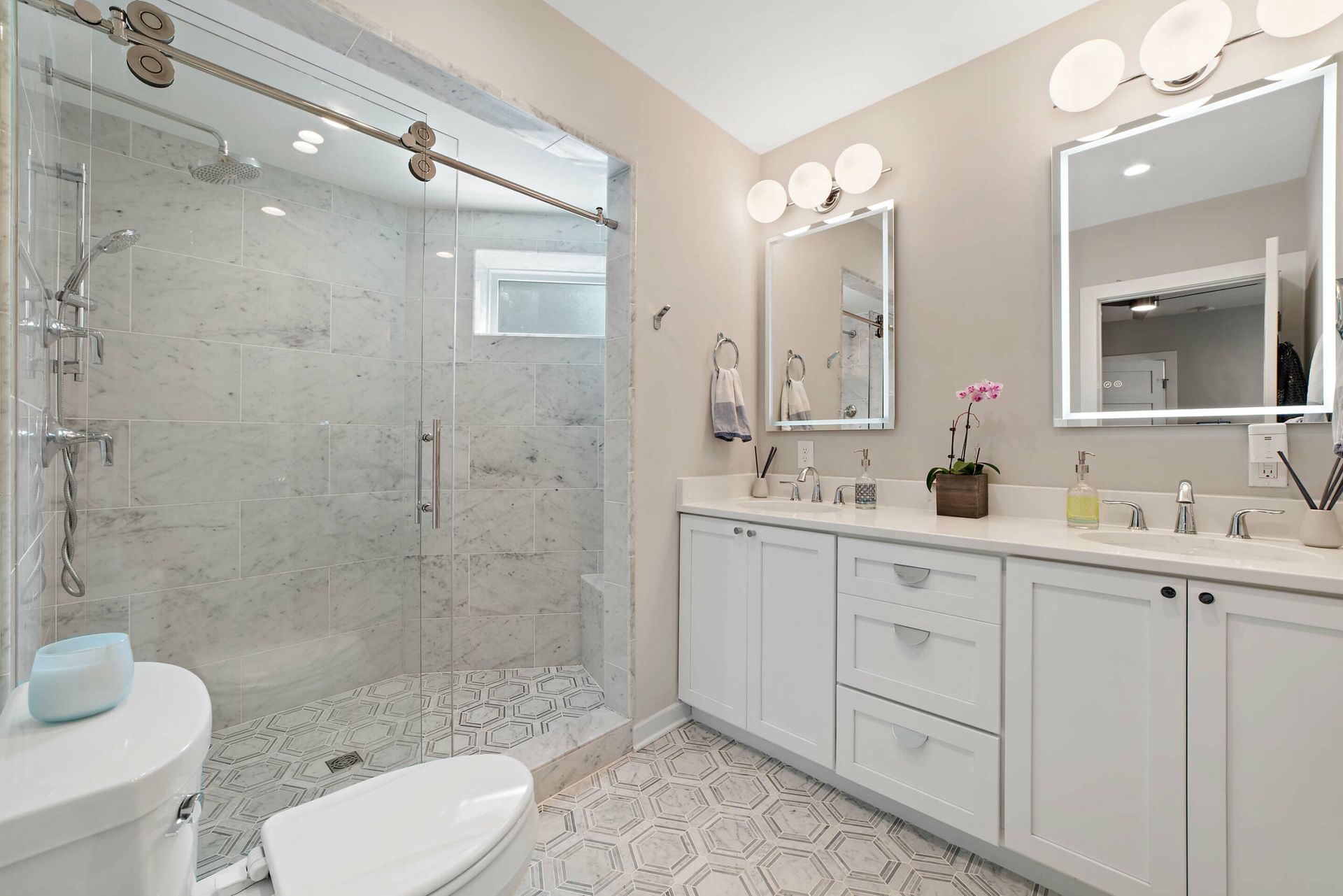 white double vanity bathroom with marble tile walk-in shower, glass doors, and modern lighting in DC home remodel
