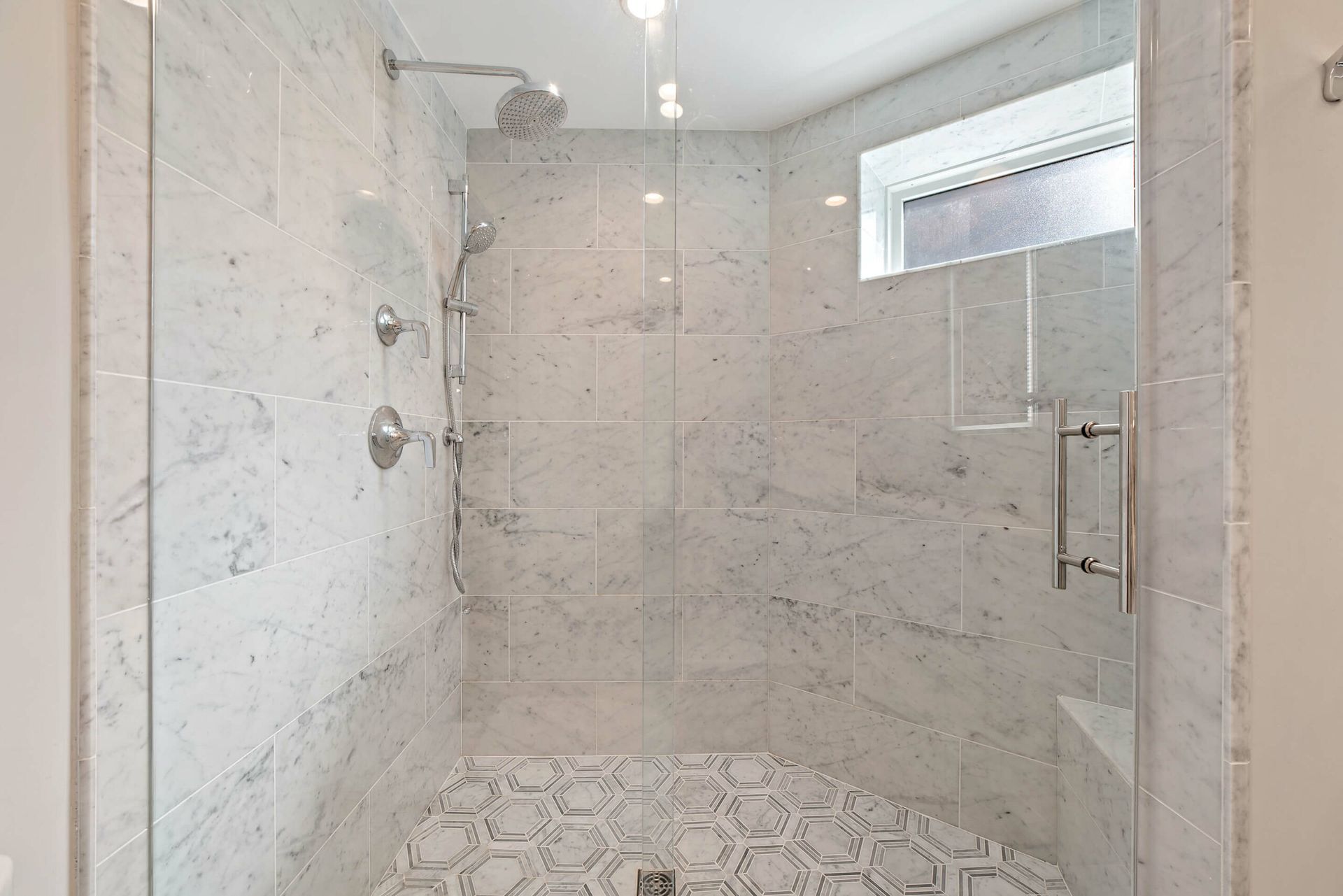 guest bathroom marble shower with dual showerheads and built-in bench
