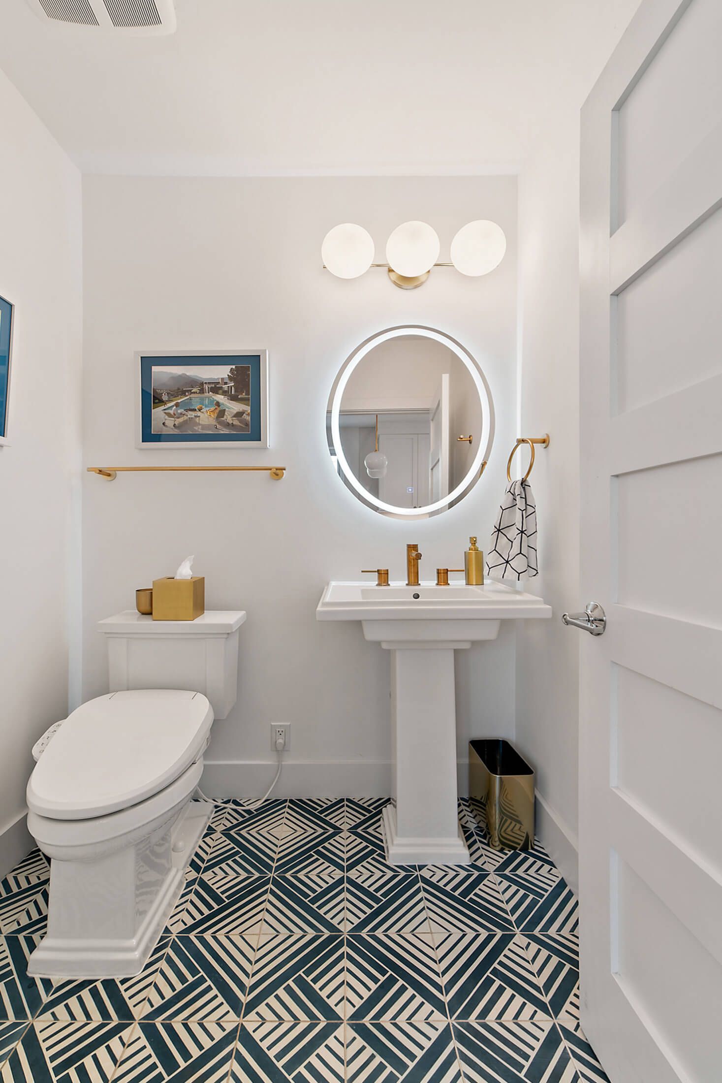 powder room with geometric tile, white pedestal sink, and brass accents