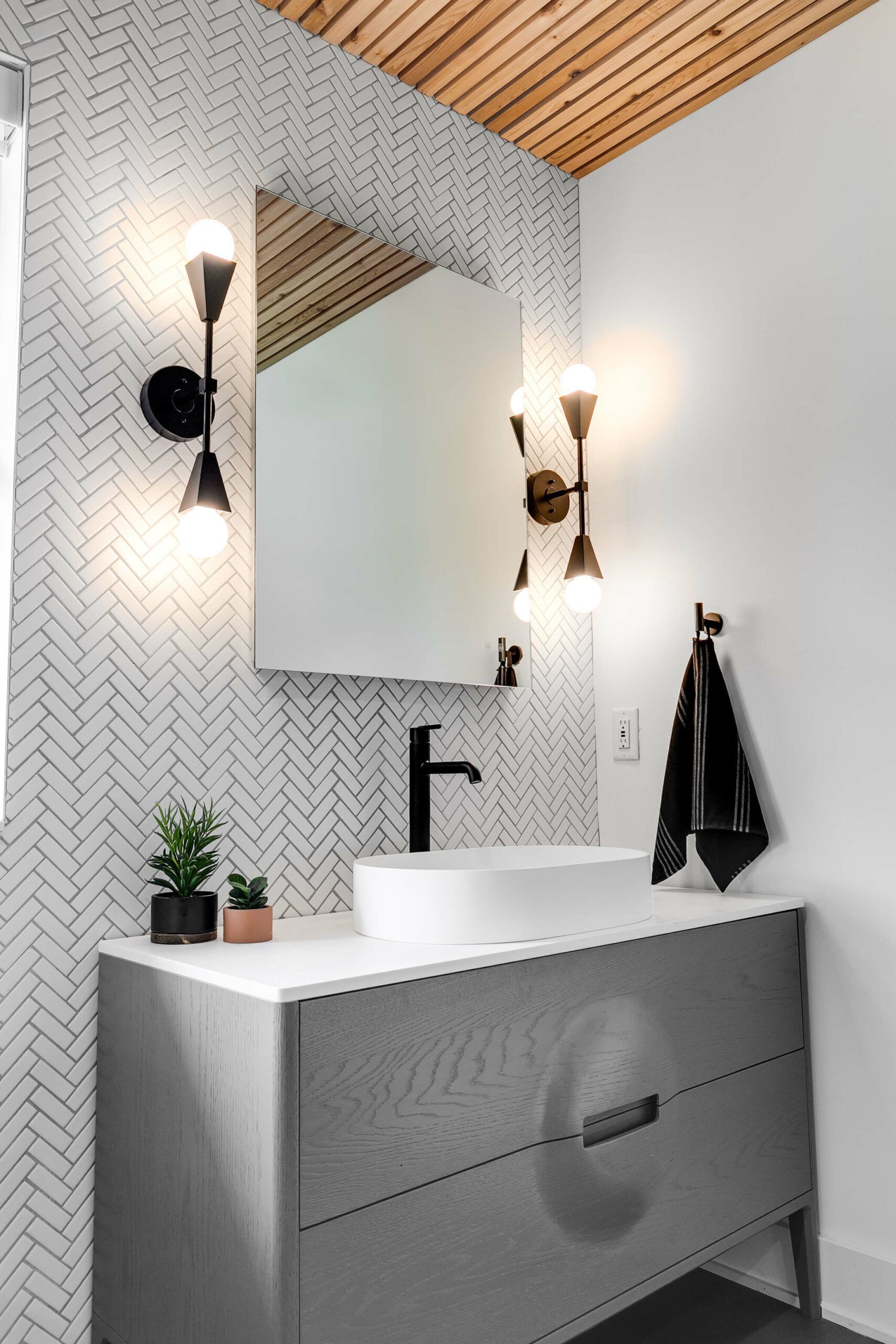 modern bathroom vanity with herringbone tile backsplash, black fixtures, vessel sink, and slatted wood ceiling