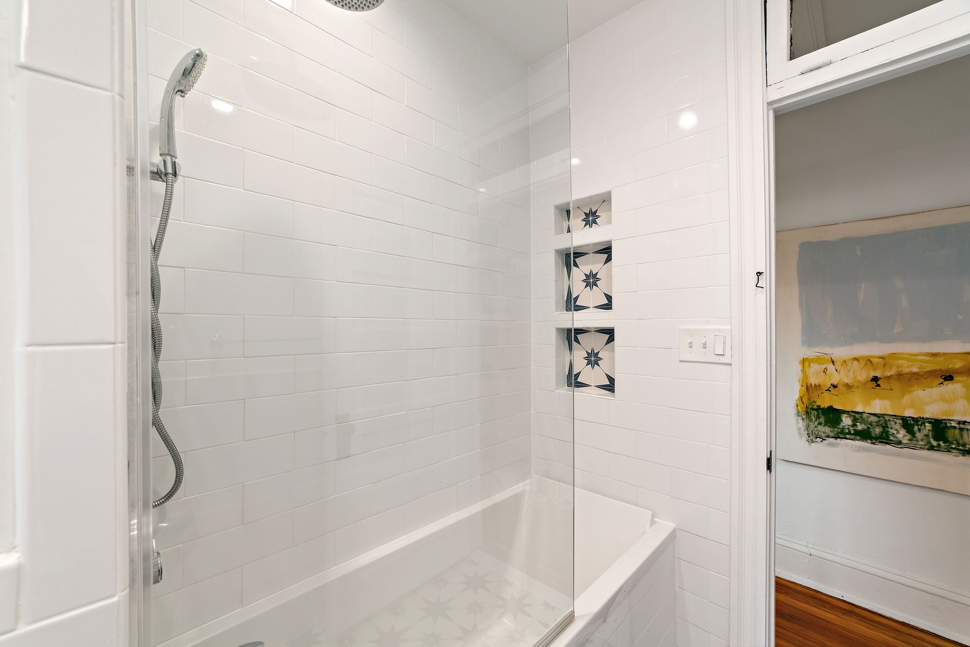 White bathtub and shower with star-patterned tile niche and matching floor in modern bathroom