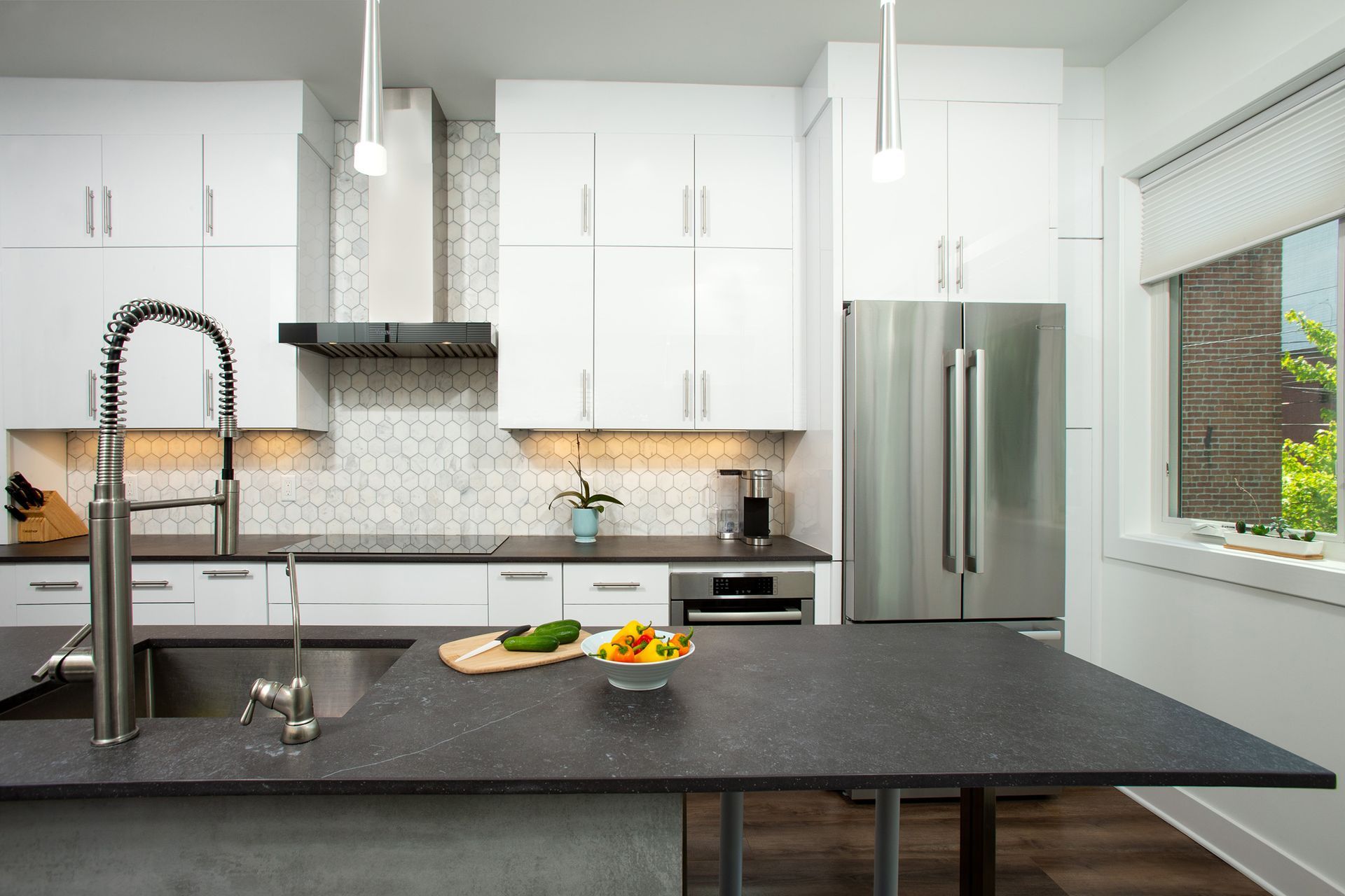 modern kitchen remodel with black countertops, white cabinets, hex tile backsplash, stainless steel appliances, large island