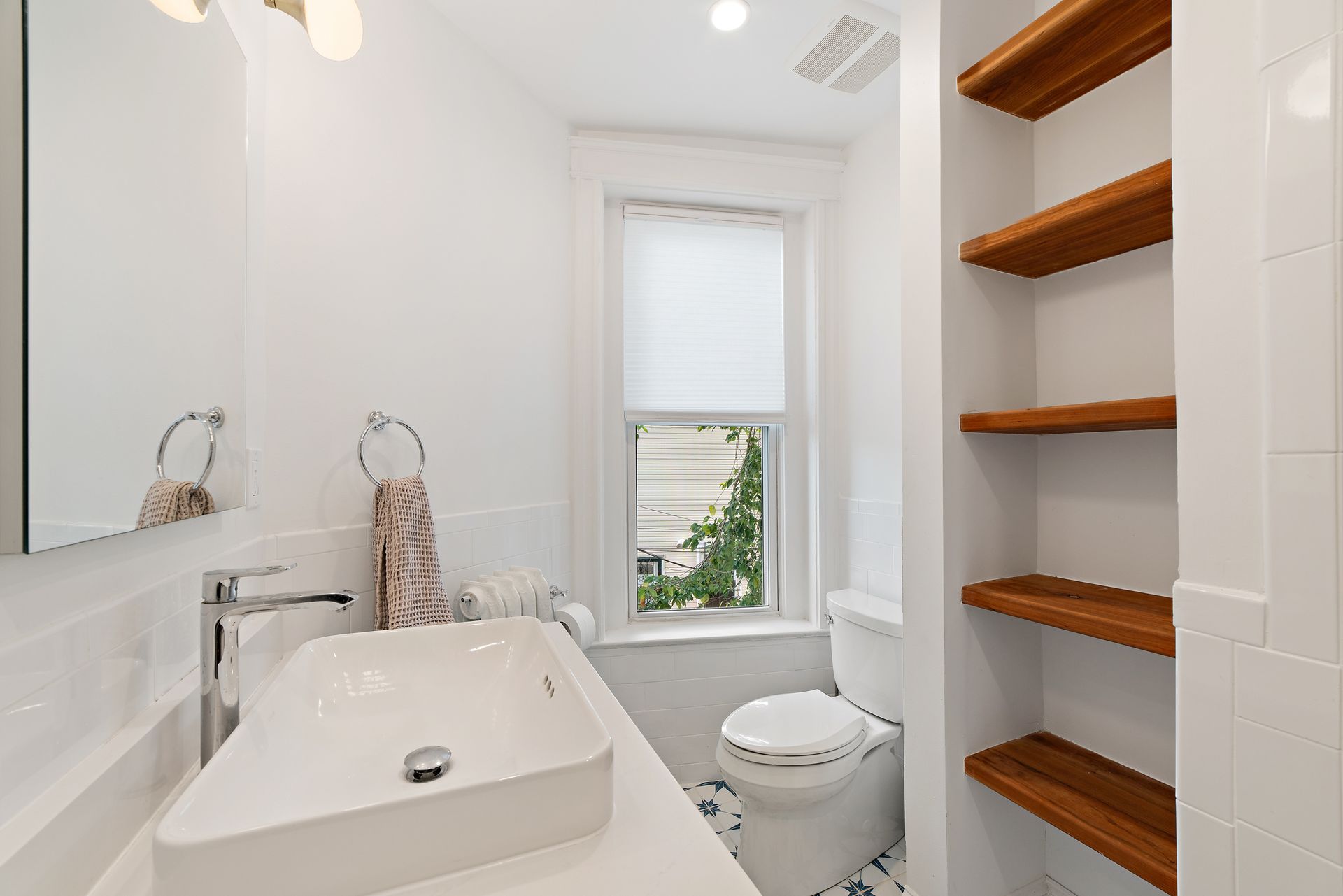 small bathroom remodel with floating wood shelves, pedestal sink, and natural light in historic Washington DC row house