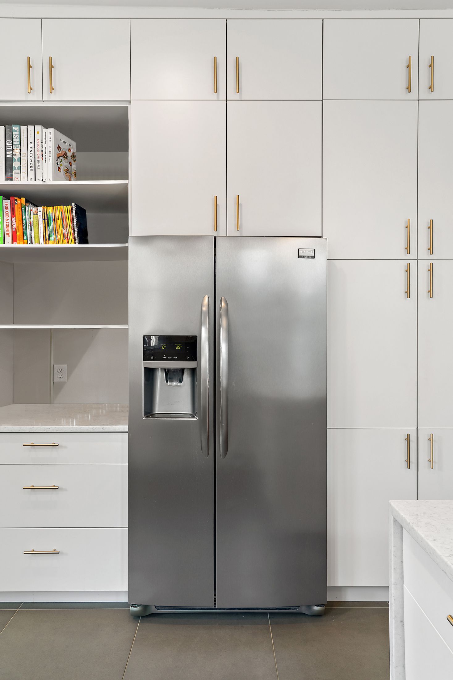 stainless steel refrigerator with white pantry cabinets and open shelving in modern kitchen remodel