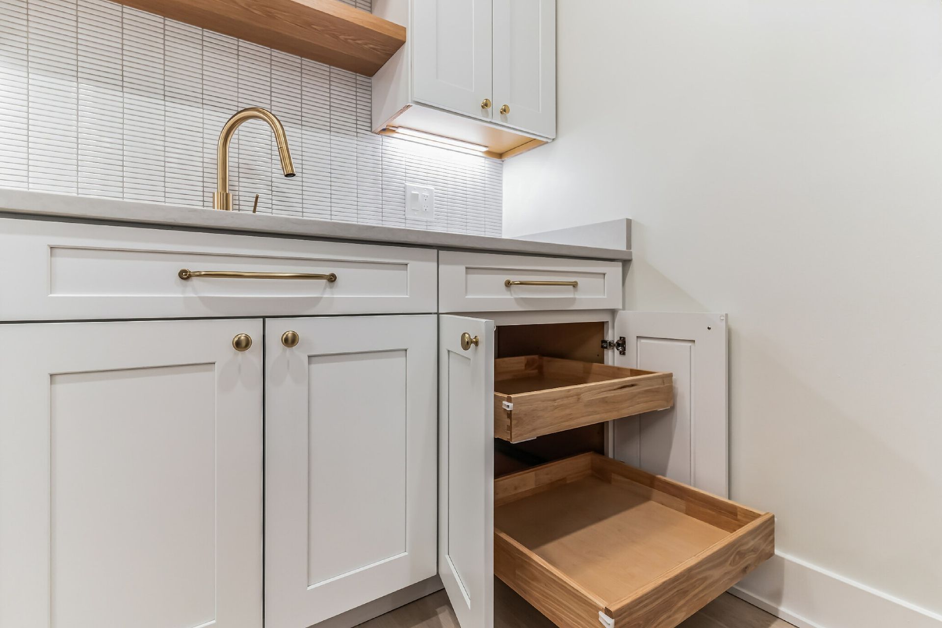 white shaker cabinets with gold hardware, under sink pull-out drawers, tile backsplash, compact kitchen storage solution
