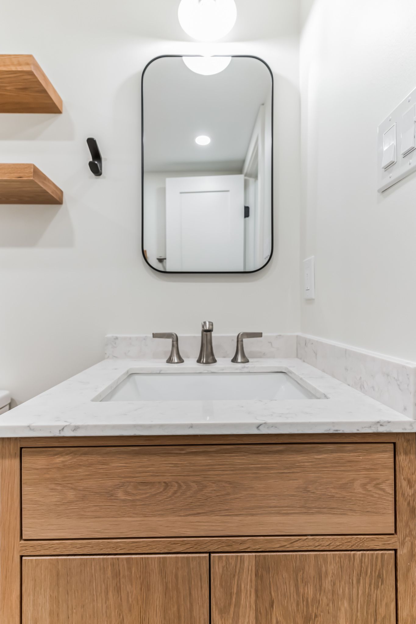 white bathroom vanity with quartz countertop, wood cabinet, black framed mirror, and brushed nickel fixtures