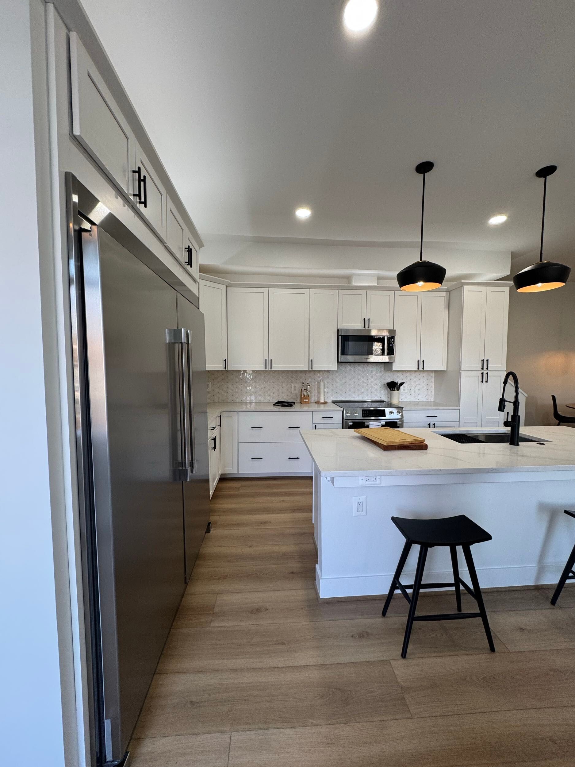 white kitchen with quartz island, modern pendant lights, black hardware, wood floors, Washington DC remodel