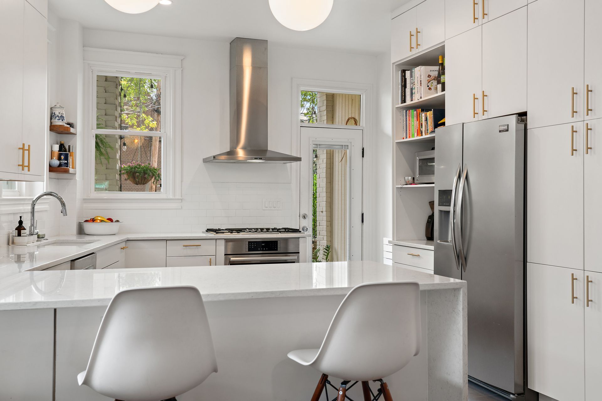 Modern white kitchen remodel in Washington DC with quartz countertops, gold cabinet pulls, stainless appliances, open shelving, and tile backsplash.