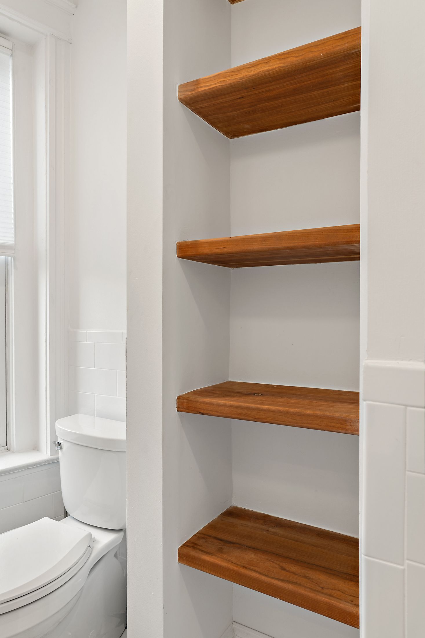 wood open shelves next to toilet in white bathroom, smart storage idea for small spaces in historic DC row home renovation