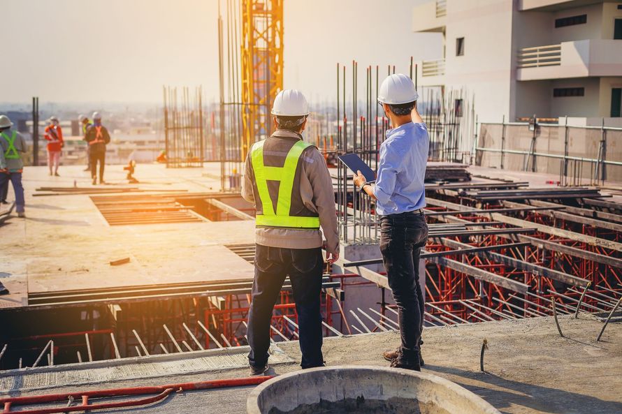 Construction worker with yellow hard hat and blueprints, construction site background.